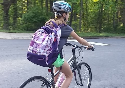Girl with backpack cycles to school