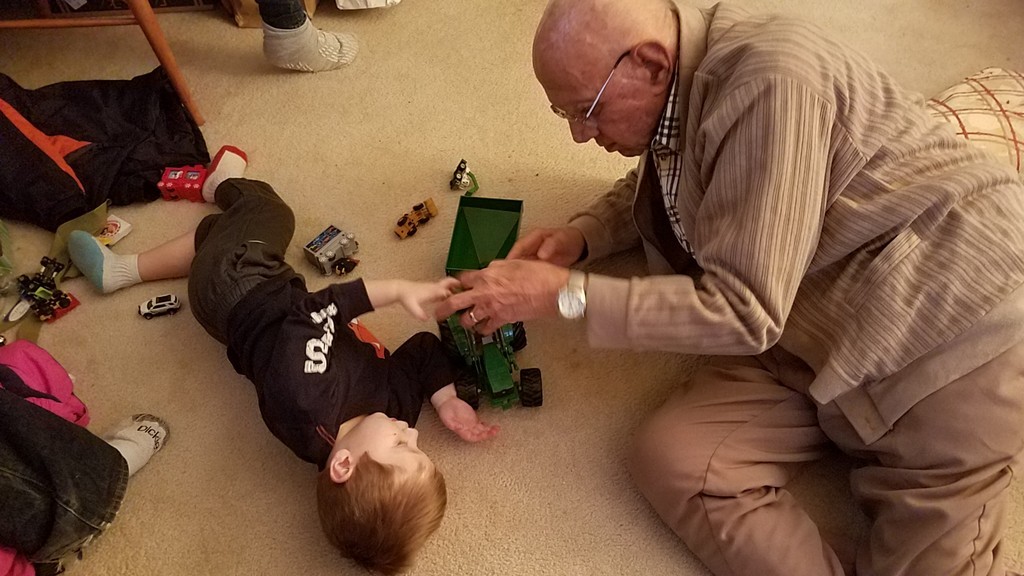 Great grandfather plays on floor with great grandson