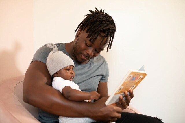 Dad holds baby and reads from book