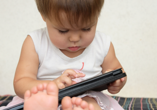 Toddler stares down at smartphone